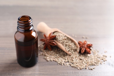 Photo of Anise essential oil and spice on wooden table