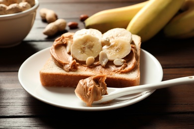 Photo of Toast bread with peanut butter and banana slices on wooden table, closeup
