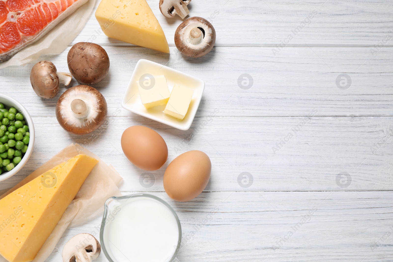 Photo of Flat lay composition with products rich in vitamin D on white wooden table. Space for text