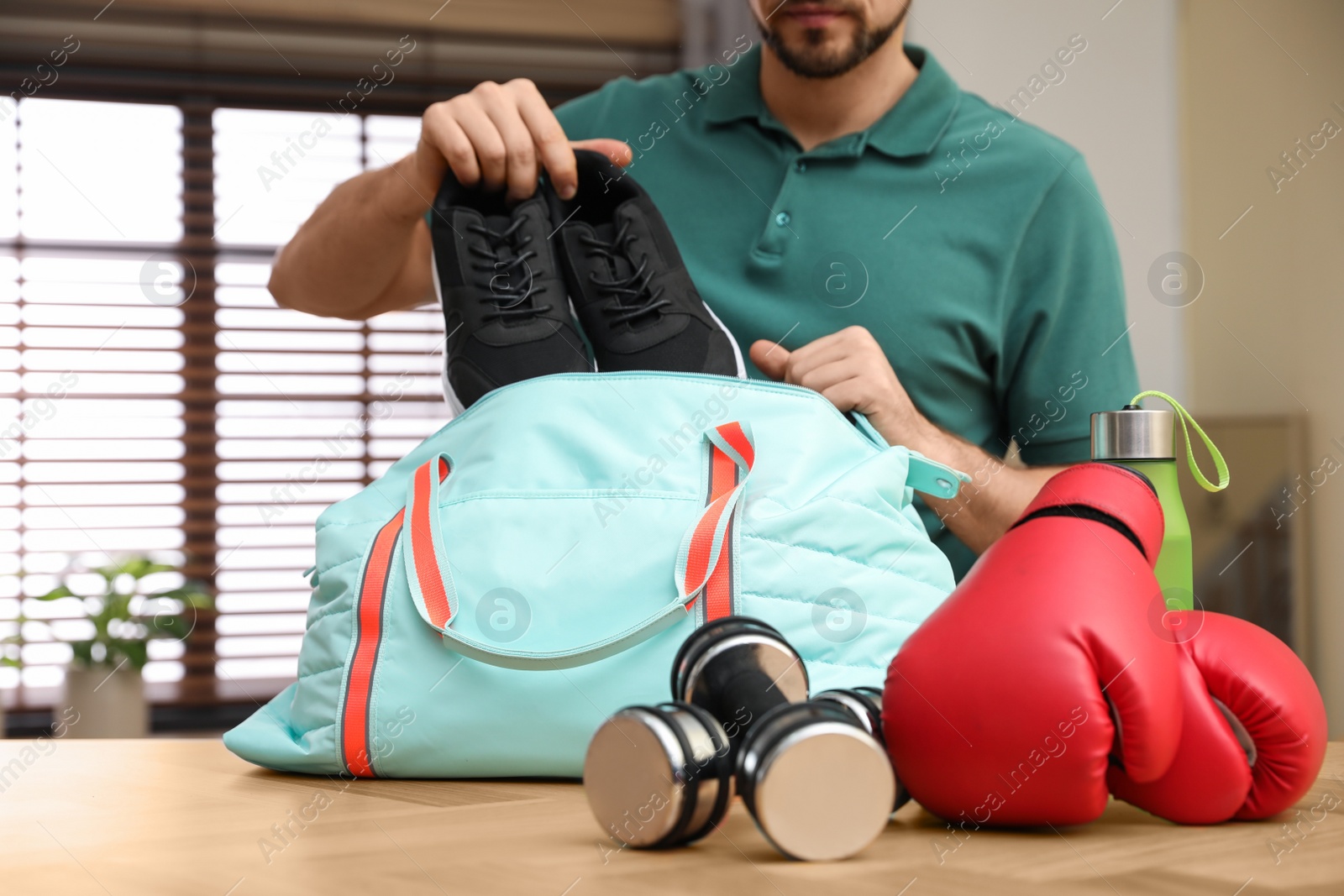 Photo of Man packing sports bag for training indoors, closeup