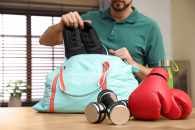 Photo of Man packing sports bag for training indoors, closeup