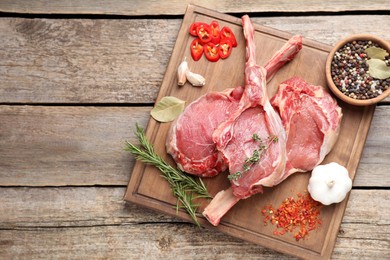 Photo of Fresh tomahawk beef cuts and spices on wooden table, top view. Space for text