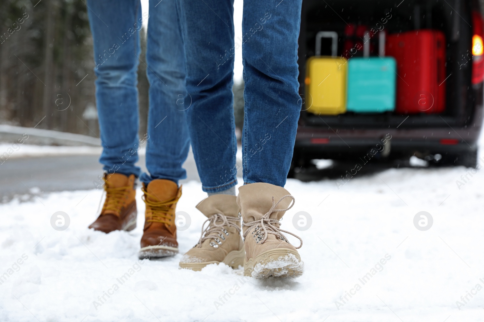 Photo of People near car with open trunk full of luggage on snowy road