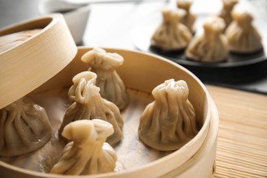 Photo of Bamboo steamer with tasty baozi dumplings on table, closeup