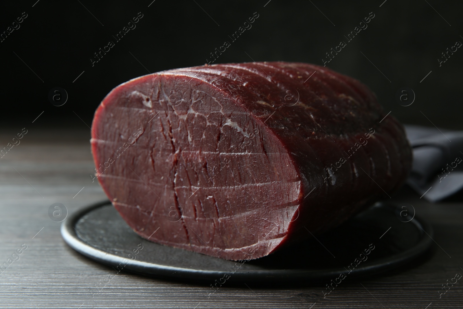 Photo of Tasty bresaola on wooden table, closeup view