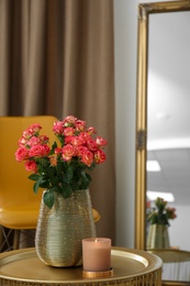 Bouquet of beautiful roses and burning candle on table indoors. Interior elements