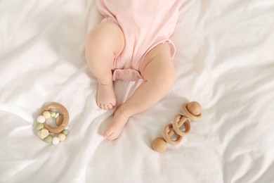 Photo of Cute baby and rattle toys on sheets, top view