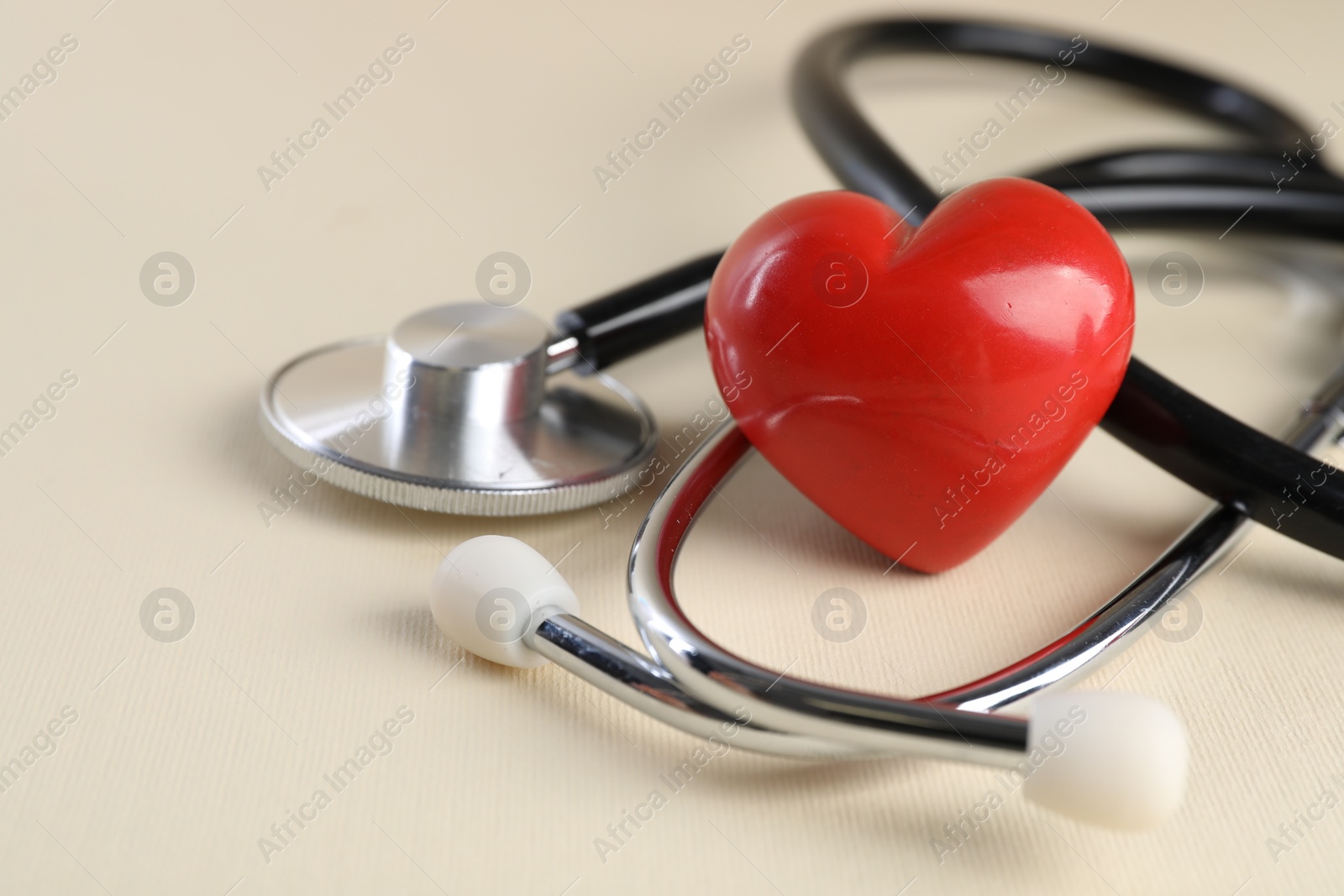 Photo of Stethoscope and red heart on beige background