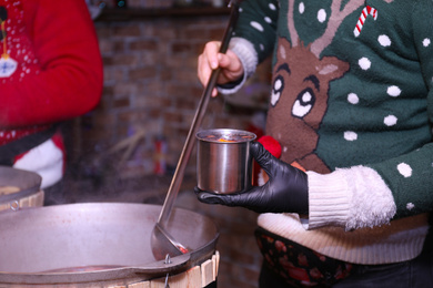 Photo of Seller with tasty mulled wine at winter fair, closeup