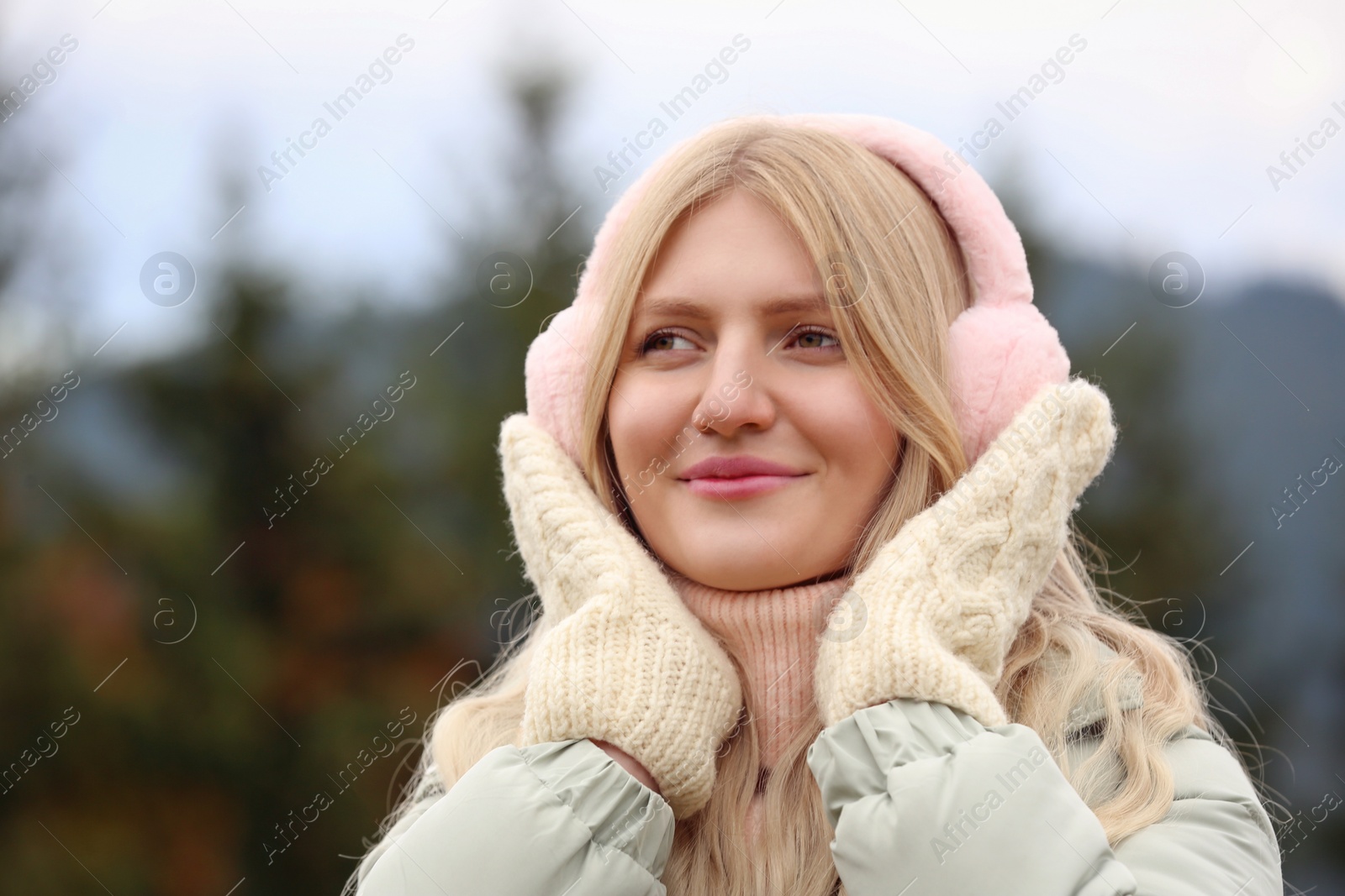 Photo of Young beautiful woman wearing warm earmuffs in mountains