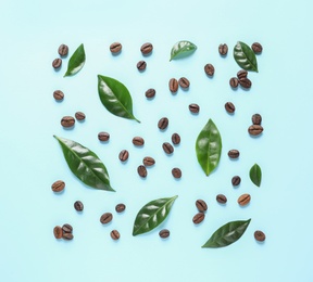Photo of Fresh green coffee leaves and beans on light blue background, flat lay