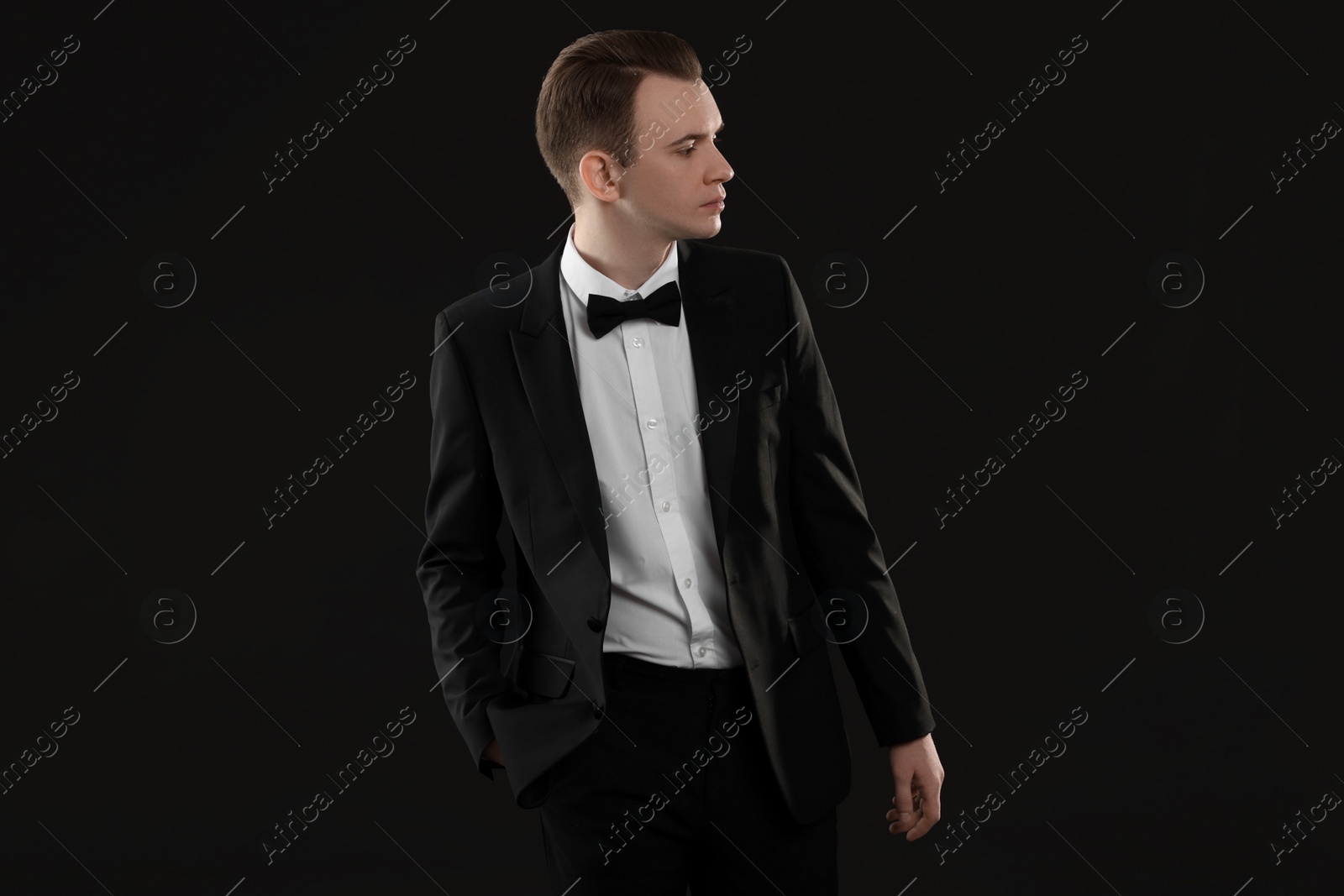 Photo of Handsome young man in stylish suit on black background