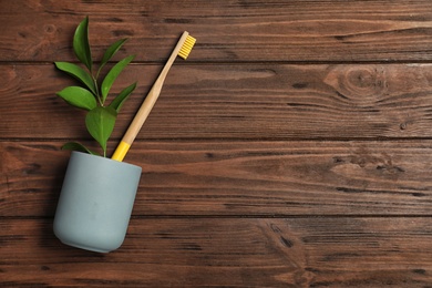 Flat lay composition with bamboo toothbrush and space for text on wooden background