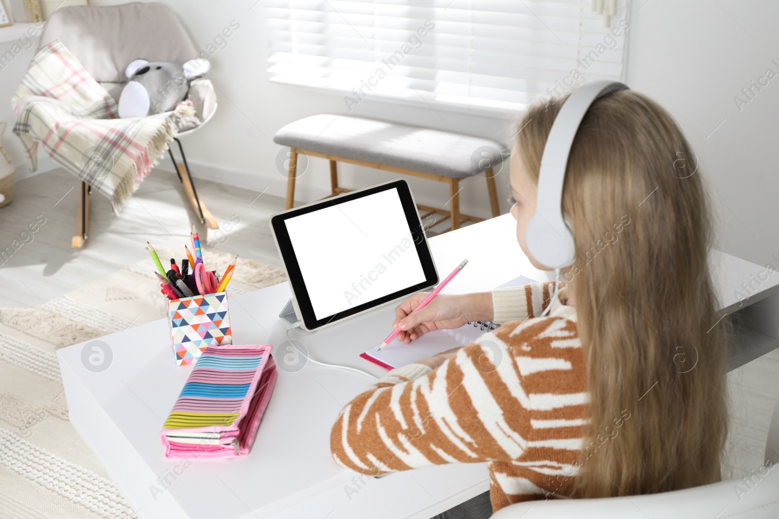 Photo of Cute little girl with modern tablet studying online at home. E-learning