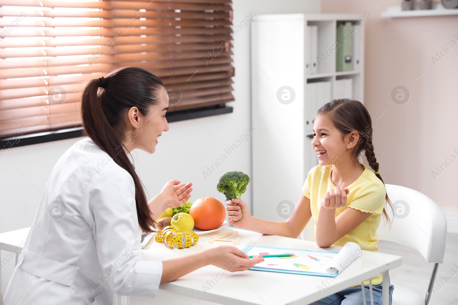 Photo of Little girl visiting professional nutritionist in office