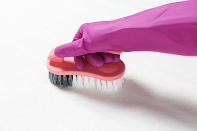 Photo of Woman in purple gloves cleaning white mattress with brush, closeup