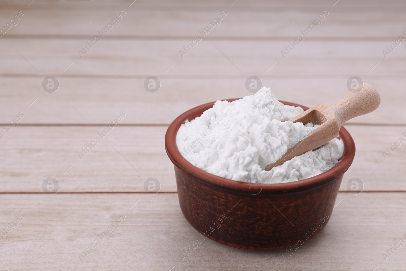 Photo of Bowl and scoop of starch on wooden table, closeup. Space for text