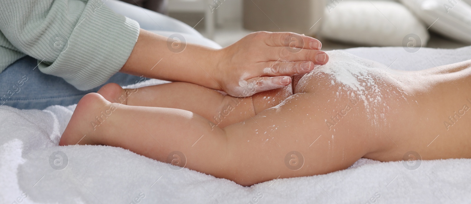 Image of Mother applying dusting powder on her baby at home, closeup. Banner design