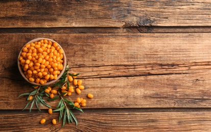 Photo of Fresh ripe sea buckthorn on wooden table, flat lay. Space for text