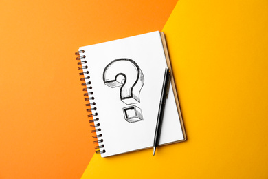 Notebook with question mark and pen on color background, top view