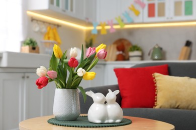 Photo of Easter decorations. Bouquet of tulips and bunny figures on table indoors