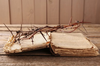 Photo of Crown of thorns and Bible on wooden table, closeup