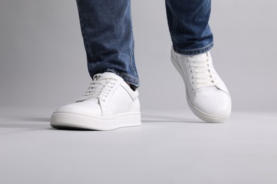 Photo of Man wearing stylish white sneakers on grey background, closeup