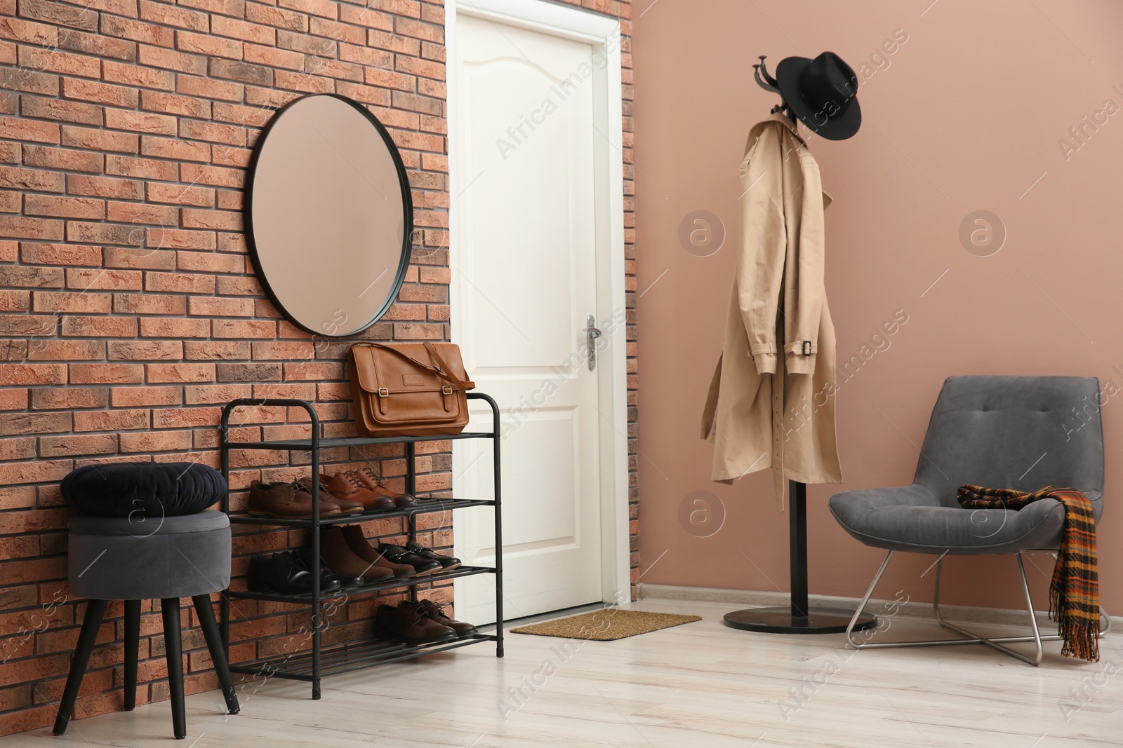 Photo of Rack with different shoes near red brick wall in hallway