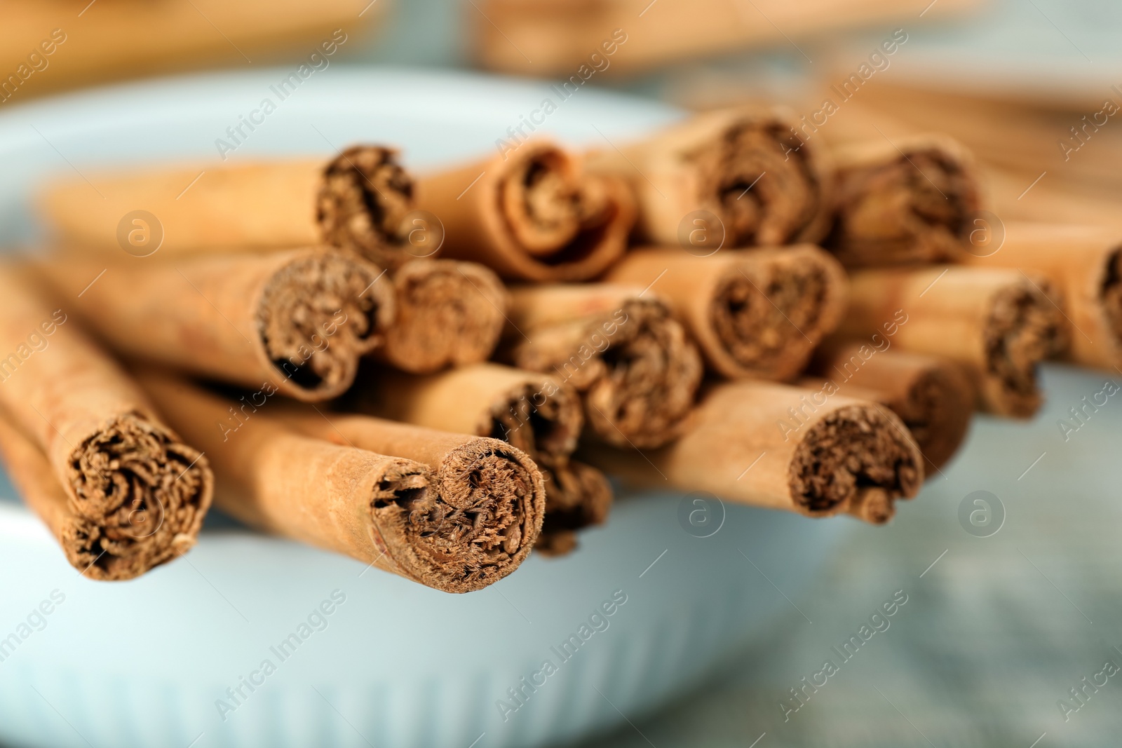 Photo of Aromatic cinnamon sticks in bowl, closeup view