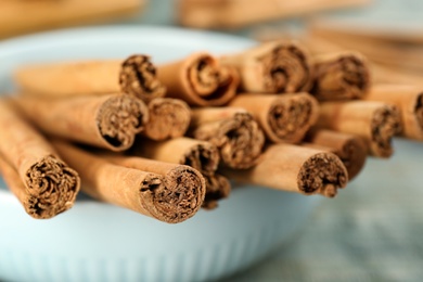Aromatic cinnamon sticks in bowl, closeup view