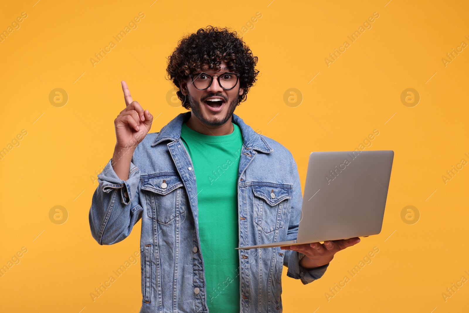 Photo of Happy man with laptop on yellow background