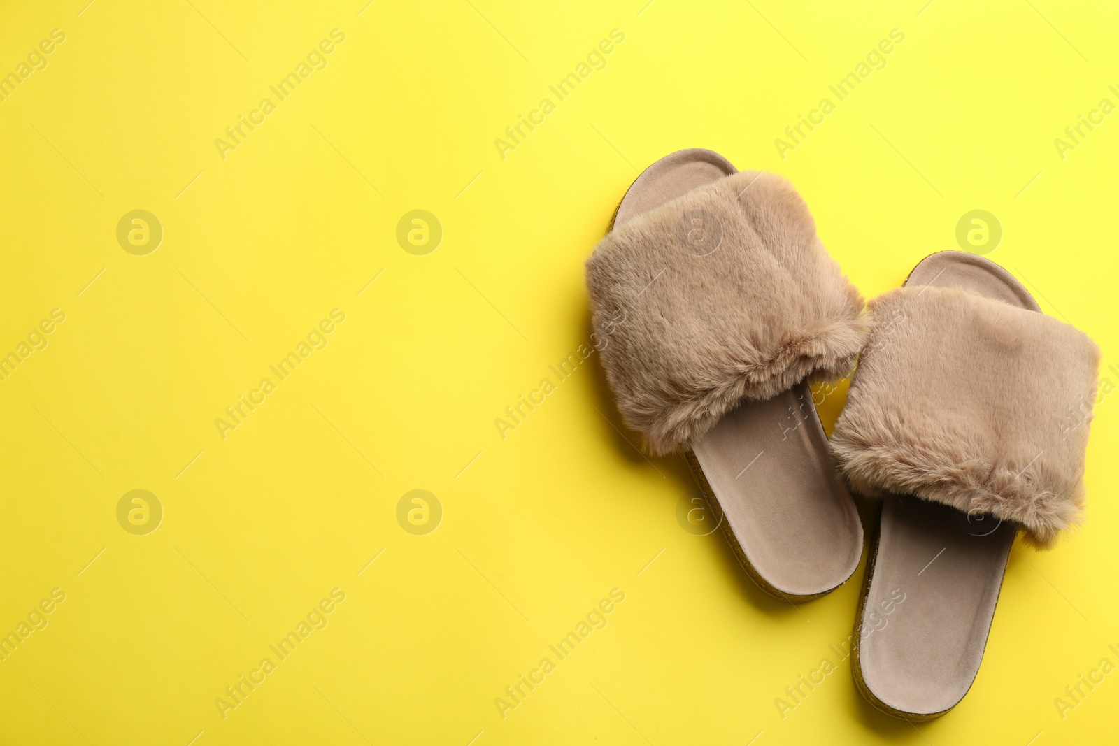 Photo of Pair of soft slippers on yellow background, flat lay. Space for text