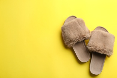 Pair of soft slippers on yellow background, flat lay. Space for text