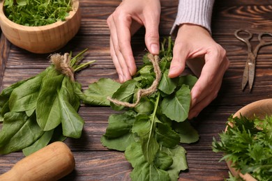 Photo of Woman with fresh green herbs at wooden table, closeup