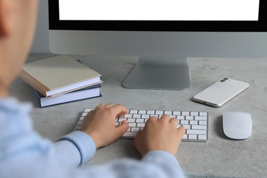 Woman working on modern computer at grey table, closeup