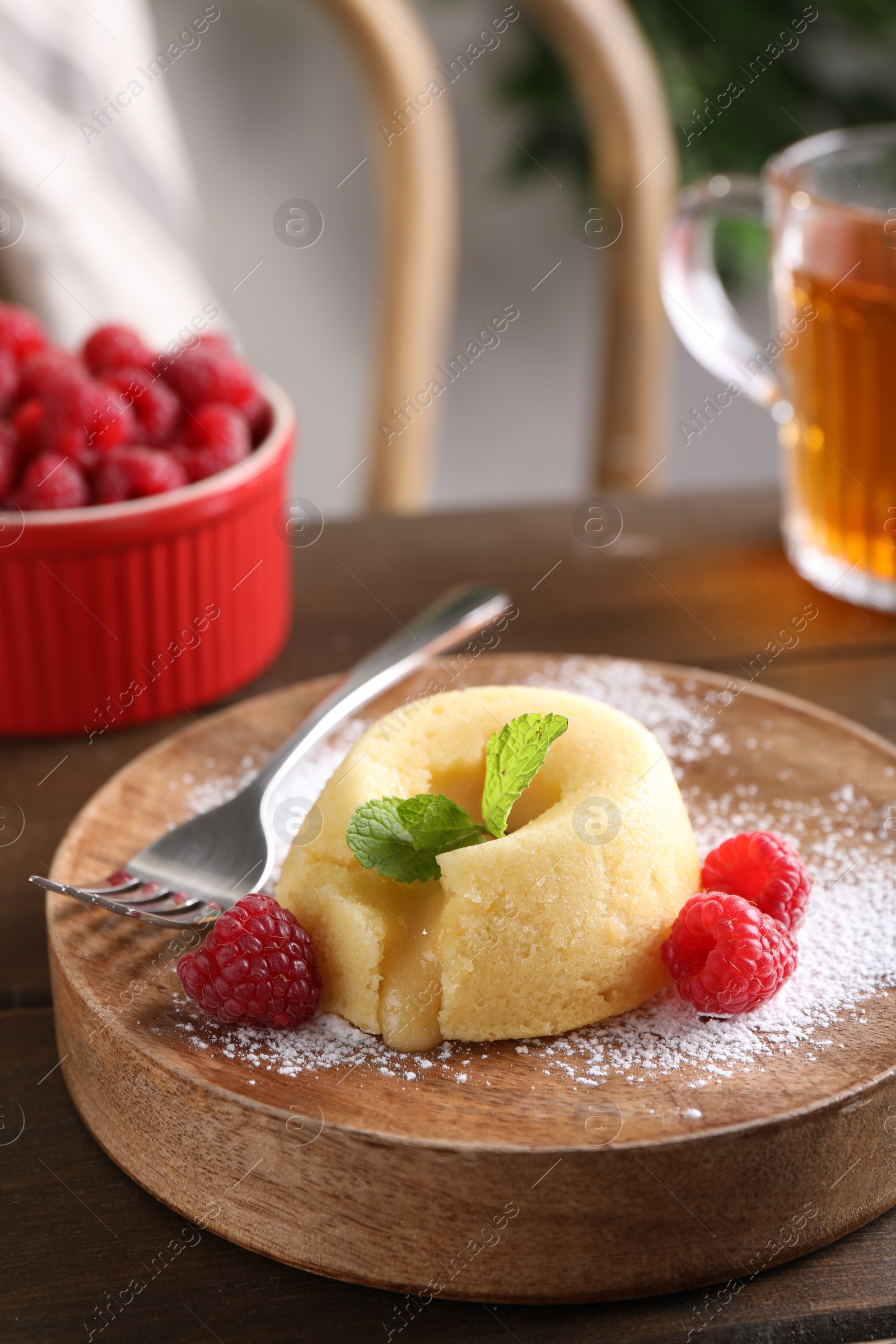 Photo of Tasty vanilla fondant with white chocolate and raspberries on table