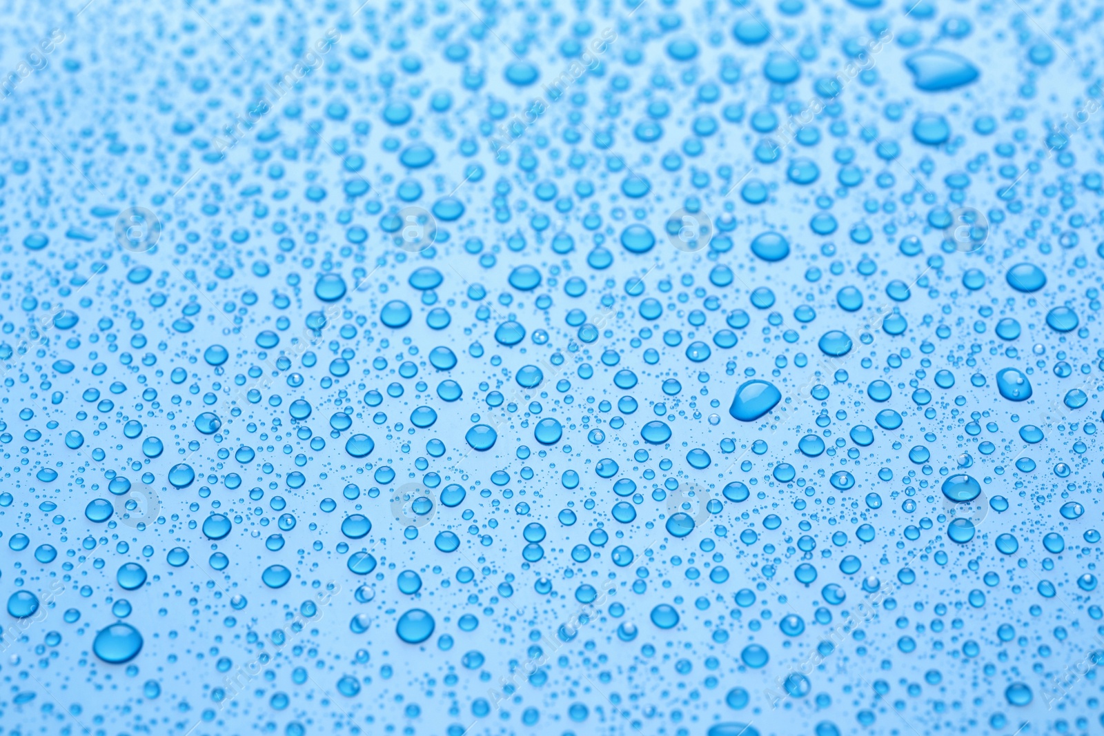 Photo of Water drops on light blue background, closeup view