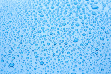 Photo of Water drops on light blue background, closeup view