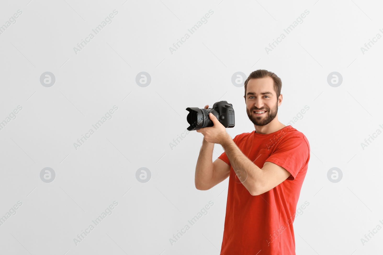 Photo of Young photographer with professional camera on white background