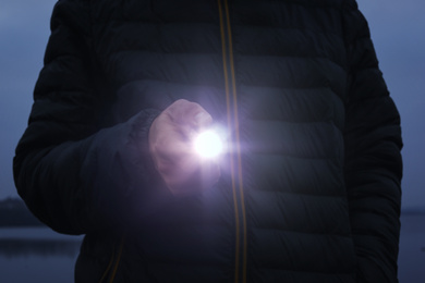 Man with flashlight walking outdoors, closeup view