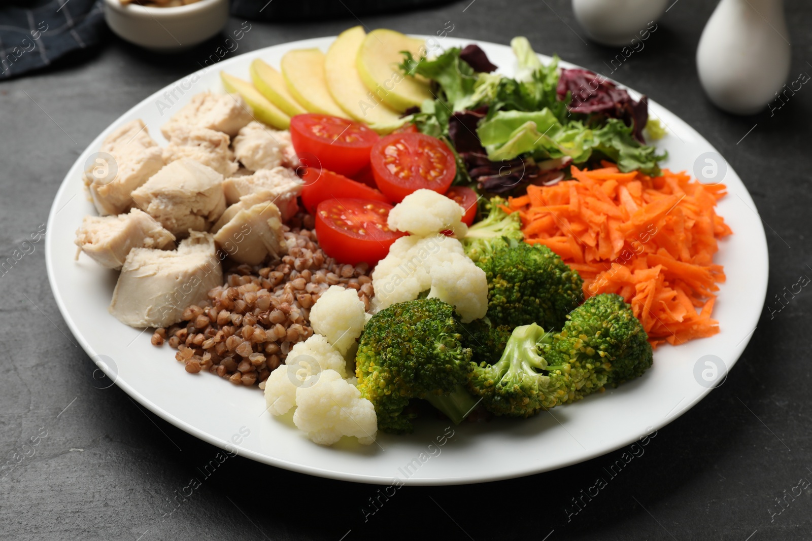 Photo of Balanced diet and healthy foods. Plate with different delicious products on black table, closeup