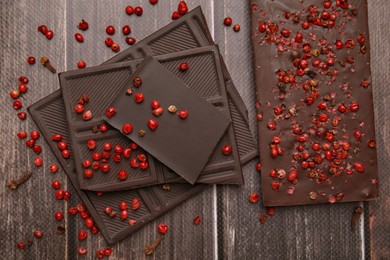 Photo of Delicious chocolate and red peppercorns on wooden table, flat lay