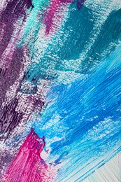 Photo of Strokes of colorful acrylic paints on white canvas, closeup