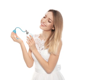 Beautiful young bride with bottle of perfume on white background