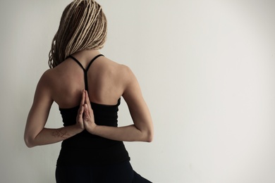 Photo of Young woman practicing yoga on light background