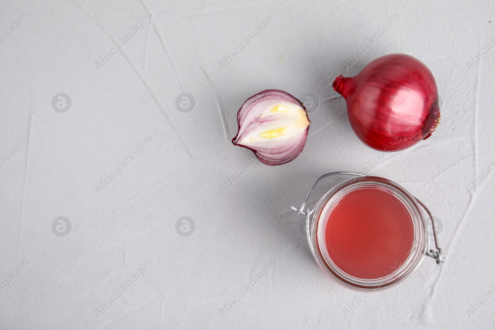 Photo of Onion syrup in glass jar and fresh vegetable on table, flat lay. Space for text