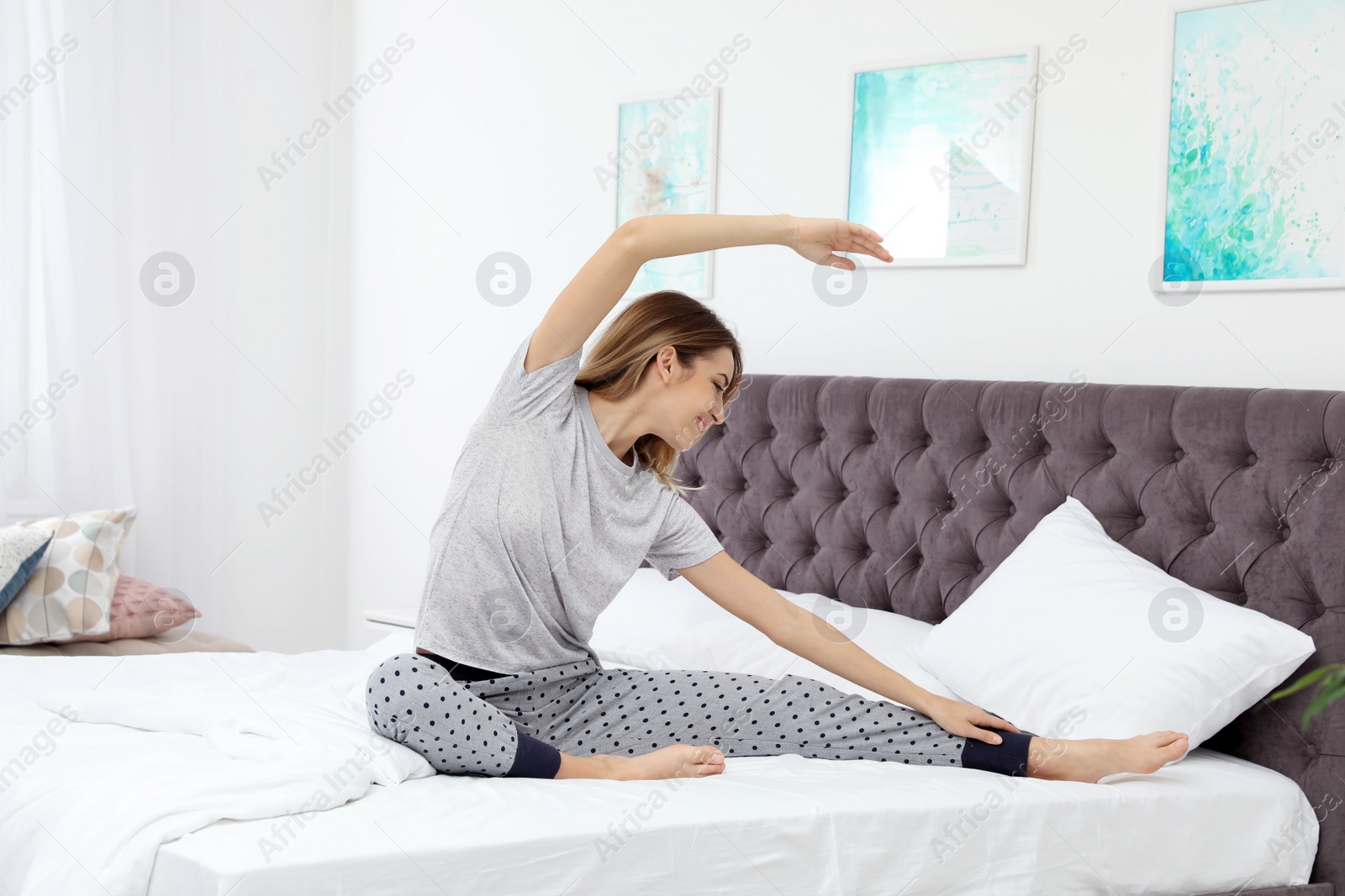 Photo of Young beautiful woman doing exercise on bed at home. Morning fitness