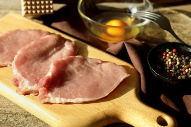 Cooking schnitzel. Raw pork slices, egg and peppercorns on table, closeup