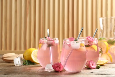 Delicious refreshing drink with rose flowers and lemon slices on wooden table