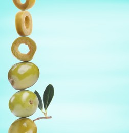 Image of Cut and whole green olives with leaves on light blue gradient background, space for text